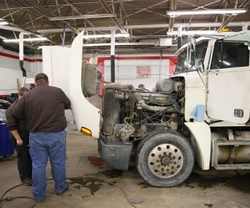 image of semi-truck with engine open, two men working on it