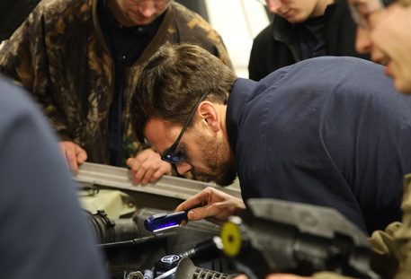 image of man bent over fixing car engine in shop