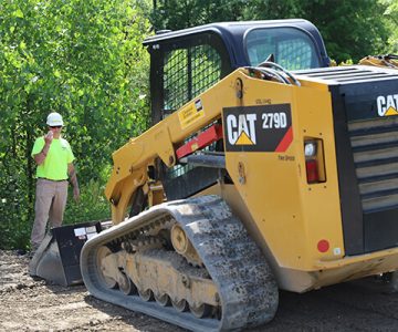 image of man standing in front of skid steer loader