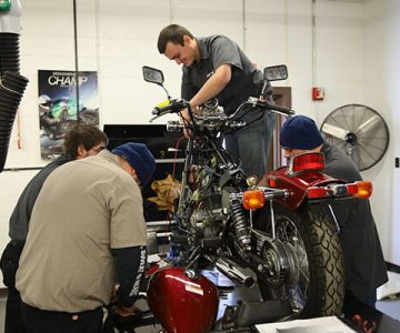 image of students working on motorcycle on table