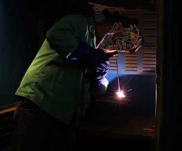 image of student welding using torch in dark lit room