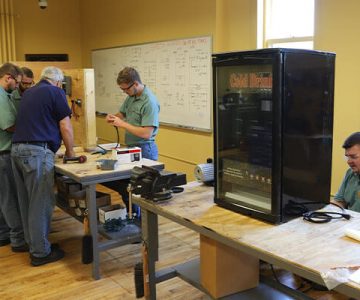 image of students working in a classroom, working on various parts of a refrigeration system