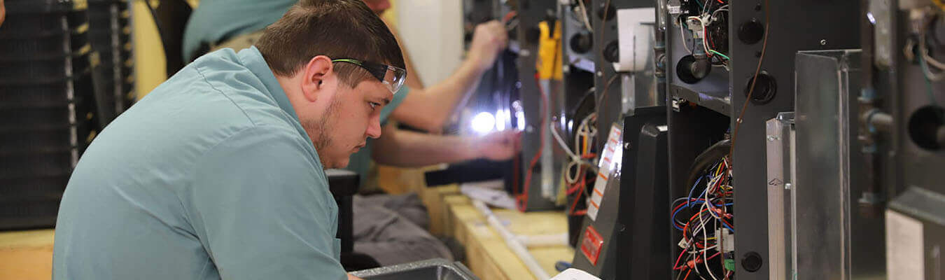 image of refrigeration and climate control student looking inside an HVAC unit