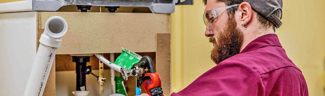 image of electrical and industrial maintenance student working on the back of a bathroom sink