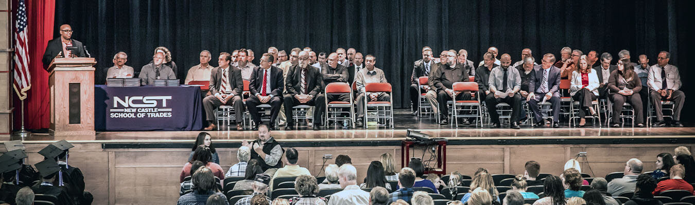 Image of NCST graduation; graduates, administration, and teachers on stage