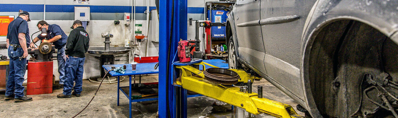 image of automotive technology lab with a car on a lift, students working in the background