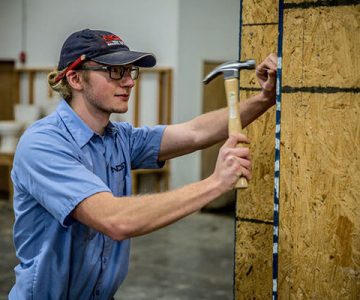 Image of building trades student hammering against wall