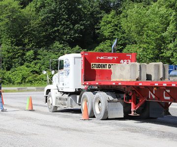 image of class a CDL flatbed truck, an instructor standing to the side