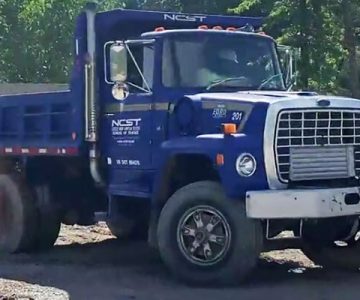 image of blue NCST dump truck on yard