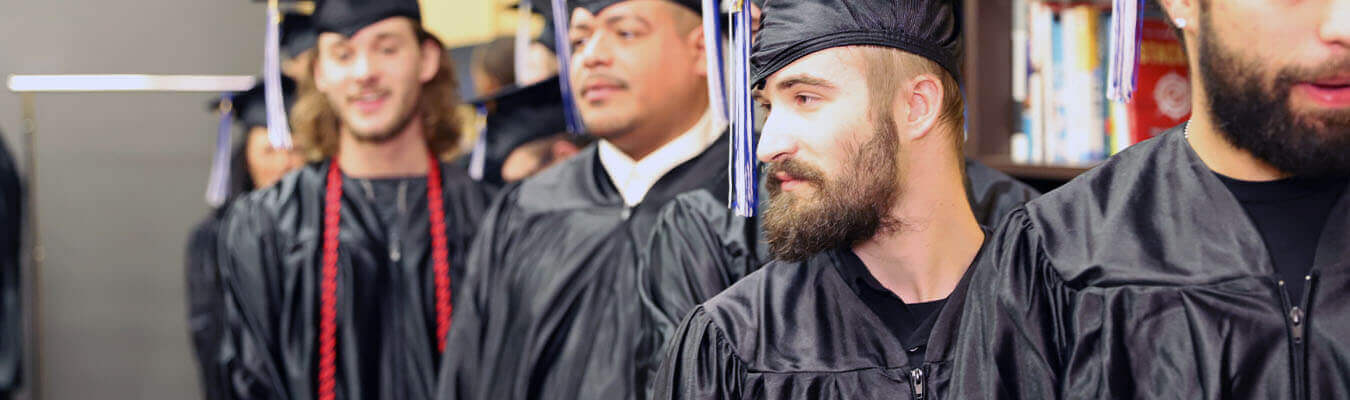 Image of NCST graduates lined up together in cap and gowns smiling