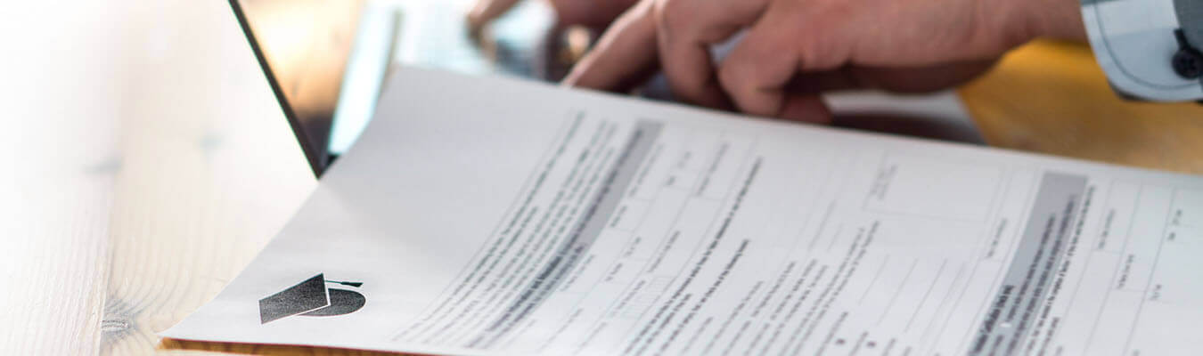 Image of person working on laptop, a tuition payment paper to the side