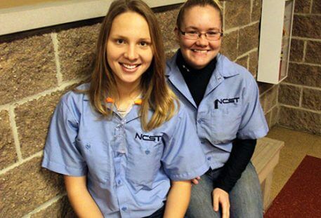 image of two female NCST students smiling while sitting on a bench