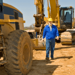 Image of Heavy Equipment With Operator walking next to it