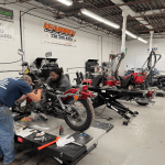 Image of two students working on a red motorcycle in a repair shop.