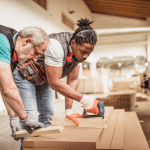 photo of 2 people using a nail gun on a board