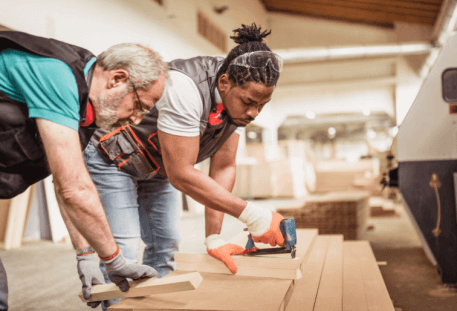 photo of 2 people using a nail gun on a board