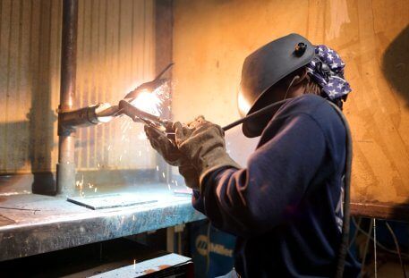 image of a welder working in a lab with spark flying.