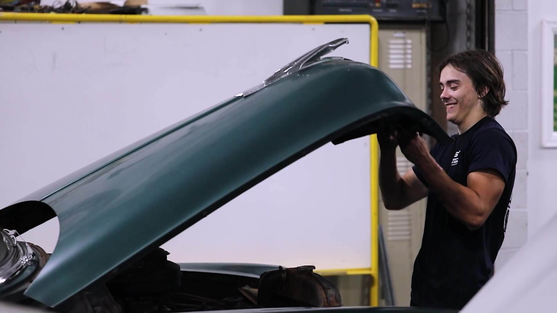 Braddick opening hood of car, smiling