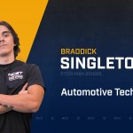 Braddick Singleton standing with arms crossed with NCST themed backdrop