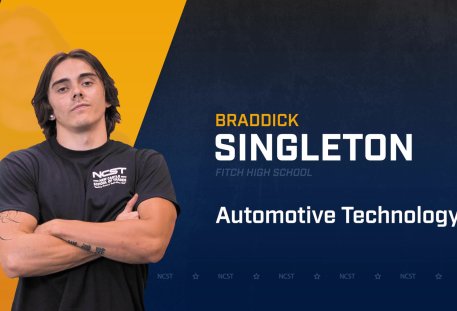 Braddick Singleton standing with arms crossed with NCST themed backdrop