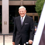 Lou holtz talking towards camera in front of building