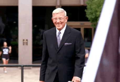 Lou holtz talking towards camera in front of building