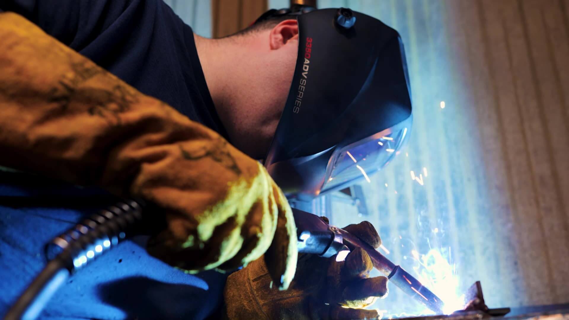 Alex welding with a torch and his mask down over his face