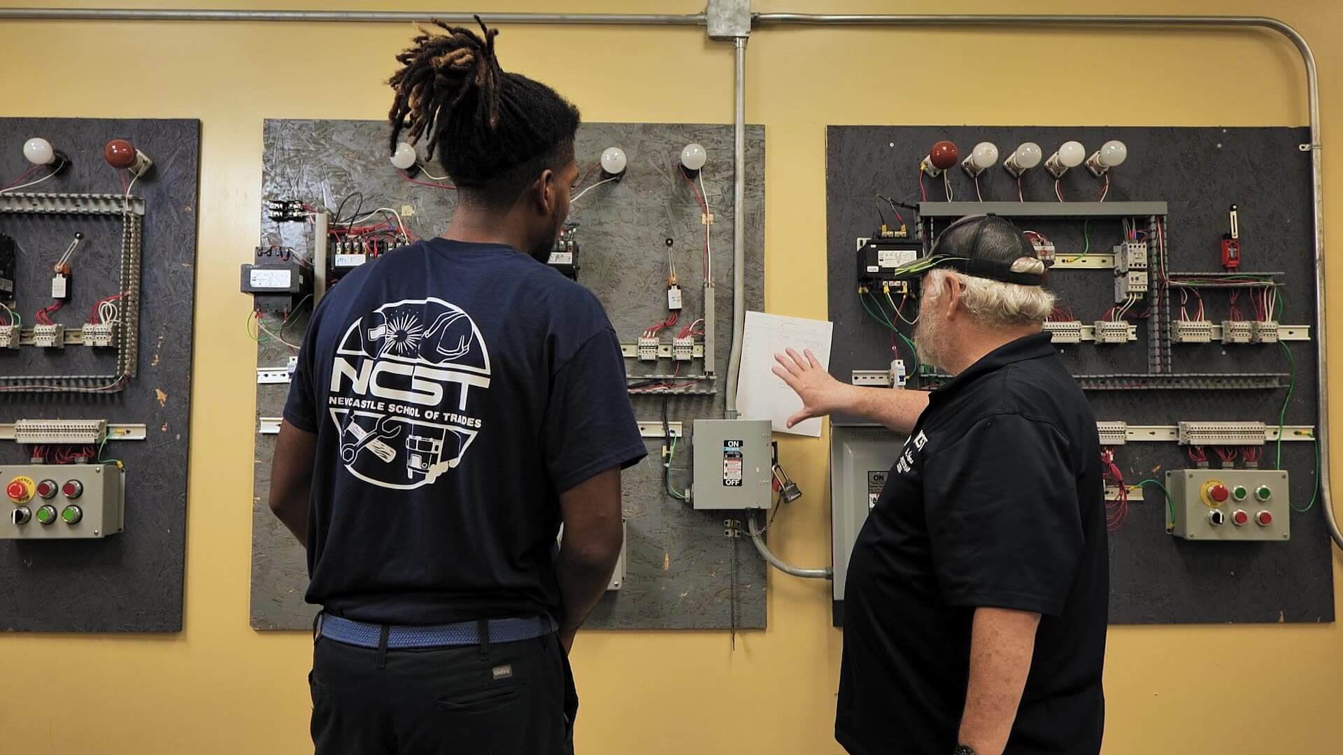 Kenneth and instructor standing at electric circuit panels