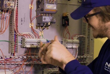 Electrical Technician student working on a wall of circuits