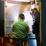 Instructor helping student in a welding lab