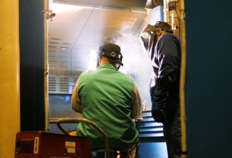 Instructor helping student in a welding lab