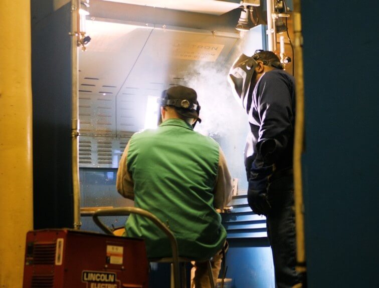 Instructor helping student in a welding lab