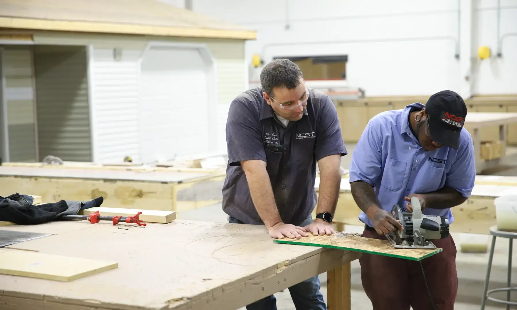 Instructor demonstrating how to use a table saw to a student