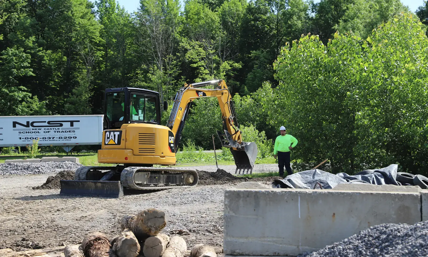Instructor watching student operate an excavator
