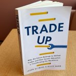 "Trade Up" book standing up on a desk