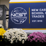The NCST stage set for Scholarship Day, with an NCST podium and a large banner behind pots of flowers