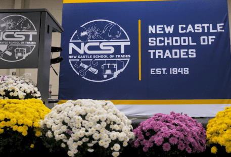 The NCST stage set for Scholarship Day, with an NCST podium and a large banner behind pots of flowers