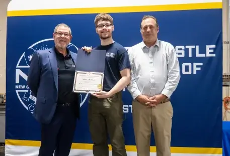NCST staff and scholarship recipient hold scholarship together